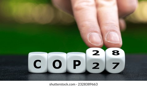 Symbol for the next climate conference. Hand turns cubes and changes the expression 'COP27' to 'COP28'.