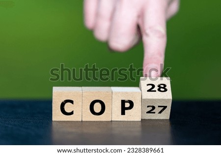 Symbol for the next climate conference. Hand turns cubes and changes the expression 'COP27' to 'COP28'.