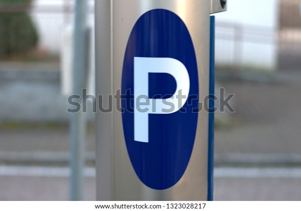 The symbol\
on this metal pole means the presence in the vicinity of a parking\
lot (the white P on a blue\
background)