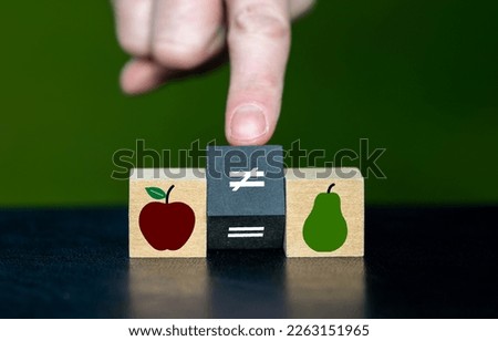 Symbol for the phrase that you can't compare apples with pears. Hand turns wooden cube and changes the equal symbol to a unequal symbol. Stockfoto © 