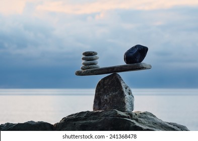 Symbol of scales is made of pebbles on the sea boulder  - Shutterstock ID 241368478