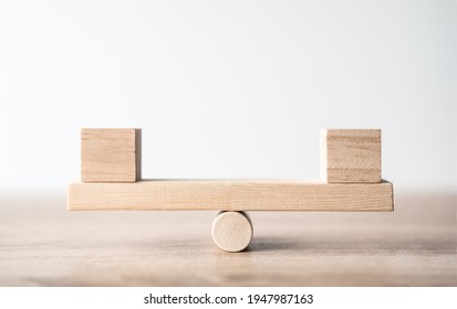 Symbol of scales. Wooden cubes figures Balancing On Wooden Seesaw. A wooden plank balancing on a wooden wheel. Concept of harmony and balance, work or family, career or relationship. Space for text