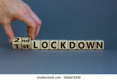 Symbol for a second lockdown. Hand turns cubes and changes the expression '1st lockdown' to '2nd lockdown'. Beautiful grey background. Medical and covid-19 pandemic concept, copy space.