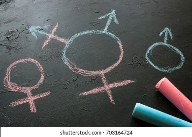 Symbol of a transgender and female and male gender symbols drawn with chalk on a black background