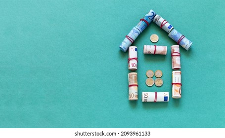 Symbolic house made of twisted euro banknotes on green background. Concept of purchasing a new home. Family budget planning. Money to buy house. Buying a house with a mortgage