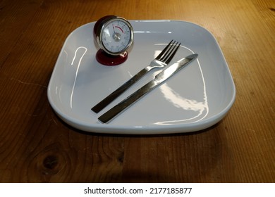 Symbolic Image For Diet And Weight Control, Interval Fasting: Empty Plate With Stopwatch And Knife And Fork.