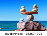Symbolic scales of stones against the background of the sea and blue sky. Concept of harmony and balance. Pros and cons concept.