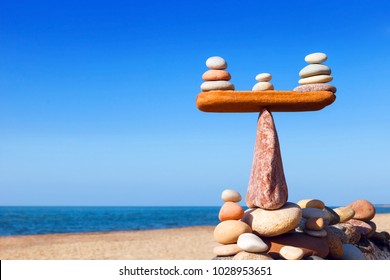 Symbolic scales of stones on a background of blue sky and sea. Concept of harmony and balance. Pros and cons concept. Work life balance - Powered by Shutterstock