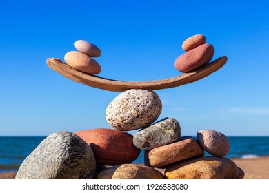 Symbolic scales of stones on the background of the sea and blue sky. Concept of life balance and harmony. Pros and cons concept