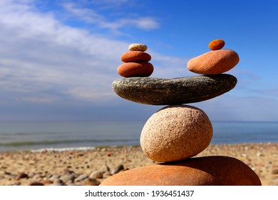 Symbolic scales of stones on the background of the sea and blue sky. Concept of life balance and harmony. Pros and cons concept