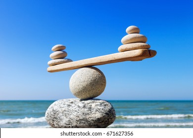 Symbolic scales of stones on the background of the sea and blue sky. Concept of harmony and balance. Pros and cons concept