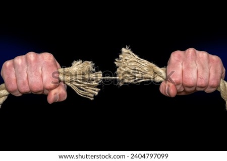 Symbolic tearing of a thick rope in front of a black background with text space