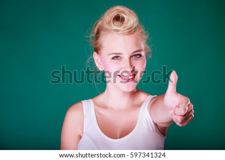 Symbols, gestures concept. Smiling young woman with pinup hair making thumb up gesture. Studio shot on green background