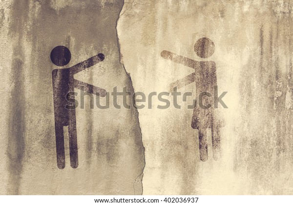 Symbols of men and women pulling hands towards each
other against the background of a concrete wall divided by cracks.
Toned
