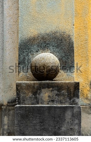 Symmetric view of the ruined facade of a forgotten building in old town of Luino, Italy. Concrete sphere on a cuboid stone block with weathered and colorful grungy texture. Lost place background.