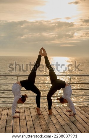 symmetrical element in gymnastics. Sporty couple doing acroyoga, fitness or pilates practice in pair in morning sea