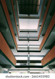 Symmetrical perspective view of a multi-story interior building with open balconies and railings, shot from the ground floor looking up. Ideal for themes of architecture, urban design, or educational 