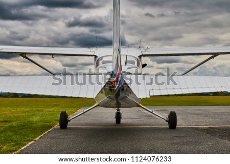 Symmetrical rear view of Cessna 172 Skyhawk 2 airplane on a runway with dramatic sky background.