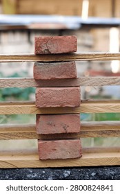 A symmetrical stack of red clay bricks alternated with wooden planks forming a vertical structure