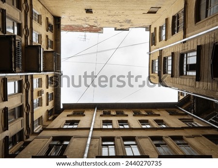 A symmetrical view of a building's courtyard with architectural details, looking up towards. Dark inner courtyard perspective, an old living houses in Saint-Petersburg, Russia