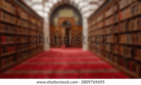 A symmetrical view down a library aisle, showcasing rows of books on shelves and a vibrant red carpet.
