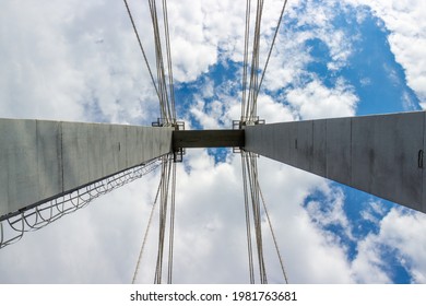 Symmetrical view with pylon and cables of cable-stayed bridge against blue sky for industrial background. Suspension bridge against sky