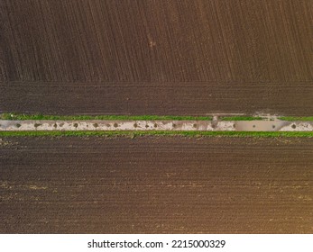 Symmetry And Lines Between Dirt Road And Plowed Field After Rain