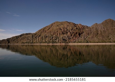 Symmetry in nature. Panorama view of the arid mountains and blue sky reflection in the lake.
