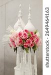 A symphony of blossoms unfolds—pink roses whispering love, white hydrangeas breathing purity. Thai garlands and golden spires rise like prayers, weaving grace into sacred silence