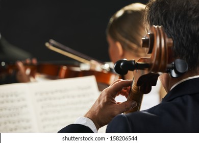 Symphony, Cellist On Foreground Playing At The Concert