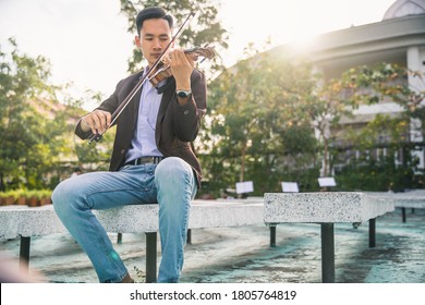 Symphony Orchestra On Outdoor Background, Hands Playing Violin. Male Violinist Playing Classical Music On Violin. Talented Violinist And Classical Music Player Solo Performance.