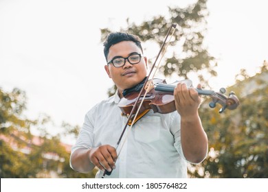 Symphony Orchestra On Outdoor Background, Hands Playing Violin. Male Violinist Playing Classical Music On Violin. Talented Violinist And Classical Music Player Solo Performance.