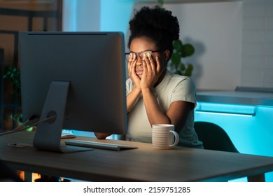 Symptoms of overworking. Young tired overworked african woman freelancer in eyeglasses working late from home, sitting in front of monitor, feeling eye strain and fatigue during computer work.  - Shutterstock ID 2159751285