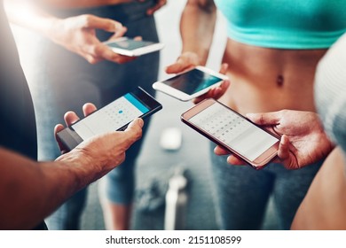 Synching their workout schedules. Closeup shot of a group of people using their cellphones together at the gym.
