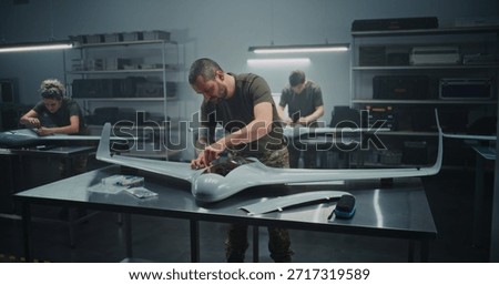 Synchronized Drone Production Team Simultaneously Assembling Large UAV. Technicians in Uniform Simultaneously Assembling UAV Workstations. Concept of Efficiency in Modern Defense Production.