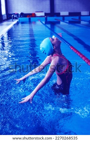 Synchronized girl working out tricks in the pool. Synchronized swimming, sports in the water. Jumps out of the water, difficult tricks