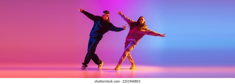 Synchronized movements. Young expressive hip-hop dancers dancing in neon. Concept of dance, youth, hobby, dynamics, movement, action, ad. Banner with copy space - Powered by Shutterstock