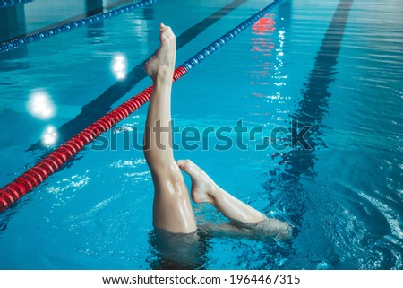 synchronized swimming athlete trains alone in the swimming pool. Training in the water upside down. Legs peek out of the water. sports figure from legs. [[stock_photo]] © 