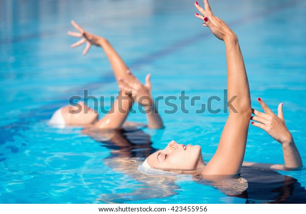 Synchronized\
swimming duet performing in swimming\
pool