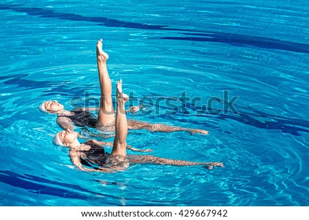 Synchronized swimming pair performing in a swimming pool
