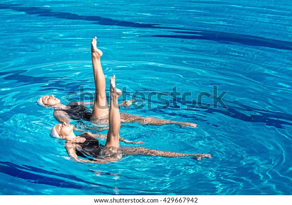 Synchronized\
swimming pair performing in a swimming\
pool