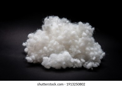Synthetic fiber, polyester fiber, siliconized holofiber, white sintepon on a black background. It is used as a filler for blankets, pillows, clothes and upholstered furniture.