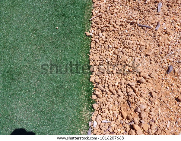 Synthetic grass in\
contrast with rocky\
soil