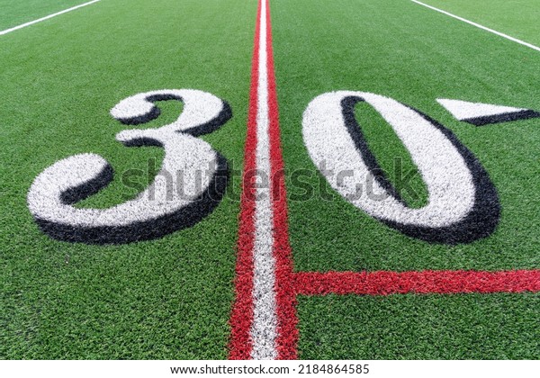 Synthetic turf football 30 yard line in white with\
black number shadow along with red lacrosse line and yellow soccer\
mid field line	