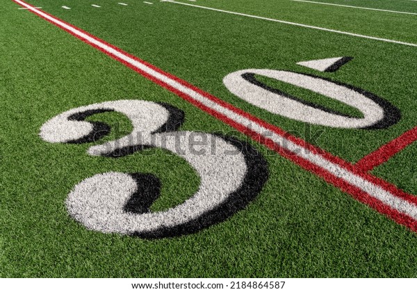 Synthetic turf  slanted football 30 yard line in
white with black number shadow along with red lacrosse line and
yellow soccer mid field
line	