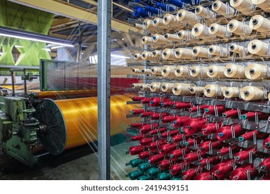 Synthetic yarns for carpet factory, carpet production, weaving looms. Interior of a Carpet Weaving Factory. Spool Sewing Thread Rack at Textile Weaving Mill. - Powered by Shutterstock