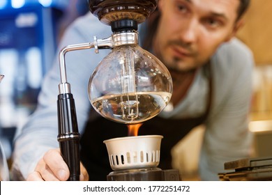 Syphon coffee brewing process. Close-up syphon is heating by fire. Barista looking at brewing process on the fire. Alternative method of coffee making. Advert for advert in social networks - Powered by Shutterstock