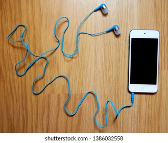 Syracuse, New York, USA - May 1, 2019: Apple IPod Touch 6th Generation With Blue Ear Buds On Wood Table 
					