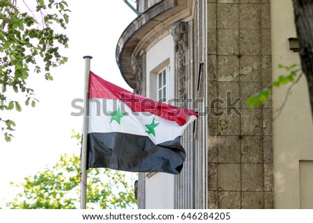 Syrian flag waving. Horizontal tricolour of red, white, and black with two green stars at the centre. The current flag was first adopted in 1958 to represent Syria as part of the United Arab Republic