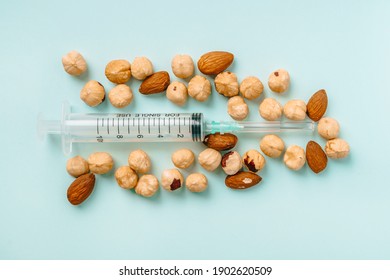 A Syringe Among A Handful Of Almonds And Hazelnuts. The Concept Of Nut Allergy And Allergen Control